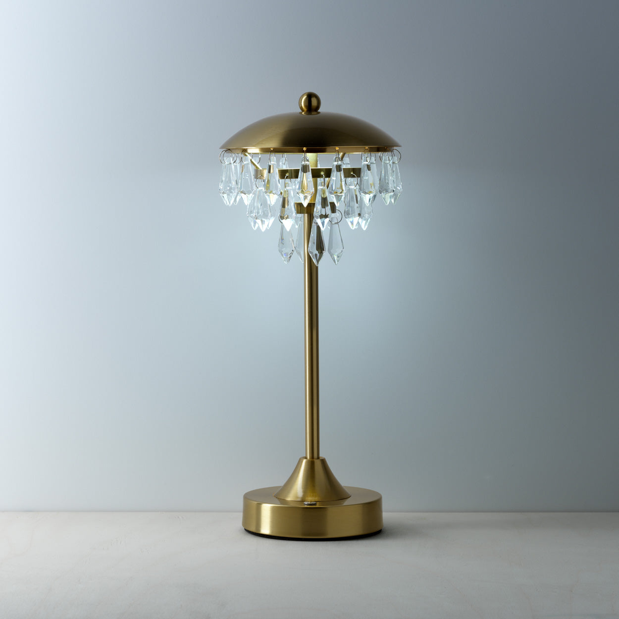 Gold table lamp with crystal accents on a neutral background