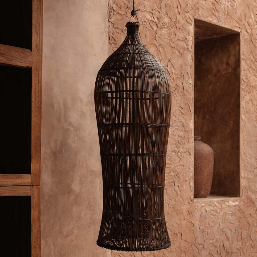 Decorative woven pendant hanging against a textured wall.