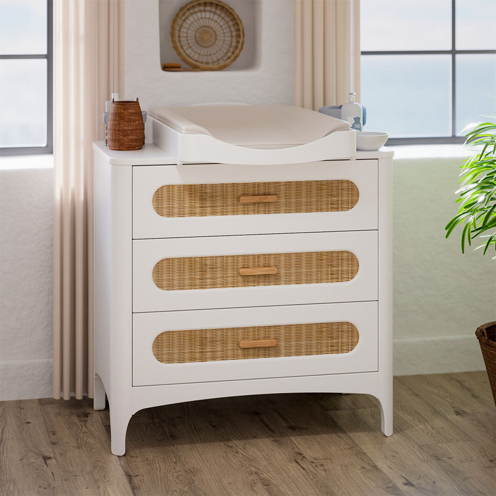 NEREIDES Chest of Drawers - Neige with wicker drawers in a room with large windows and a plant.