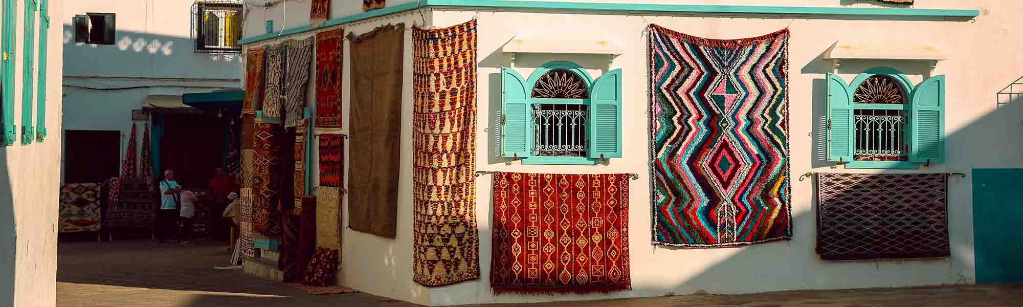 A large number of colorful handmade rugs hanging on the walls of houses