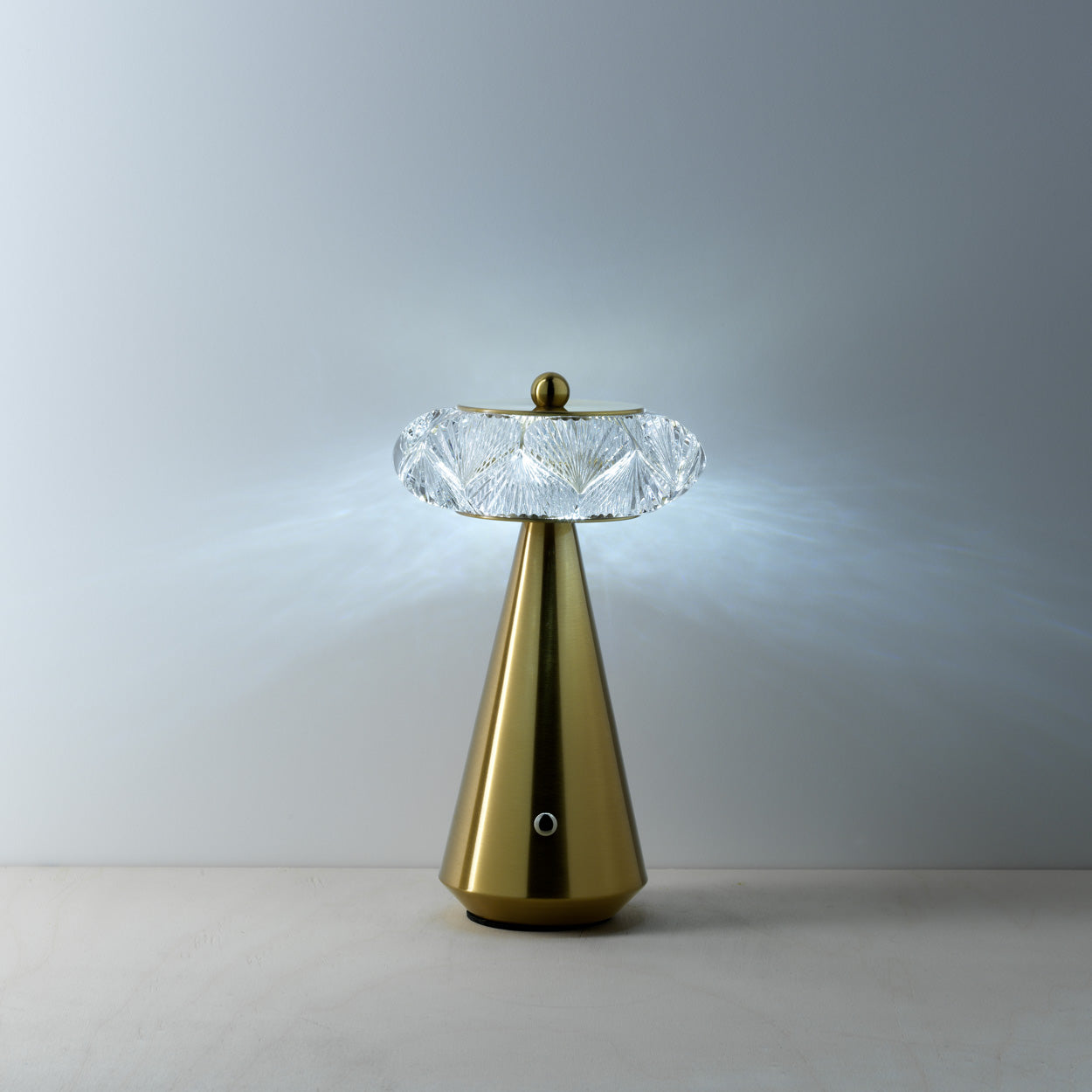 Decorative lamp with gold base and diamond shape glass on a plain background