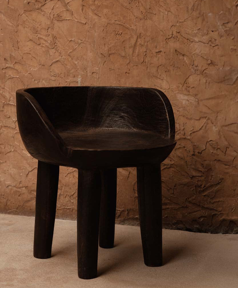 Dark walnut wooden chair against a textured brown wall