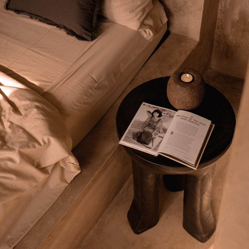 Bedroom scene with a bed and a dark walnut side table featuring an open magazine.