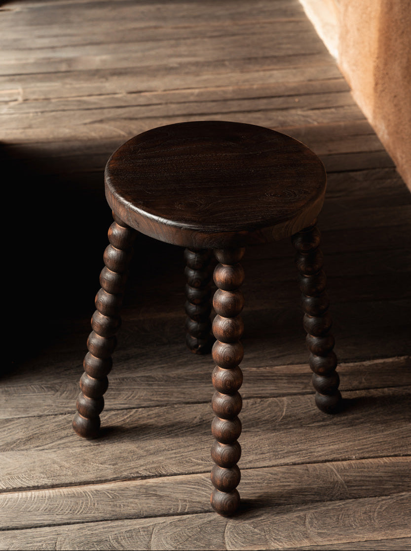 Wooden stool with spiral legs on a wooden floor