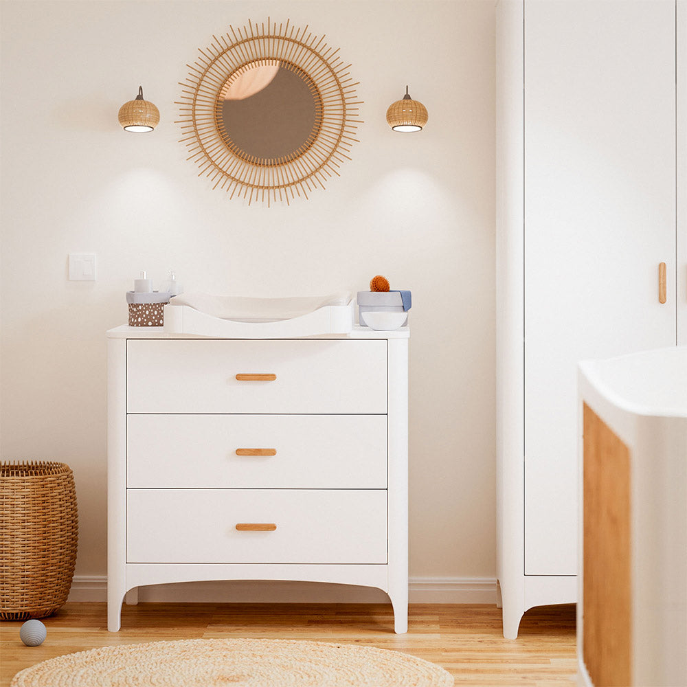 NEREE Chest of Drawers - Neige with wooden drawers in a room with a round mirror and wicker basket.